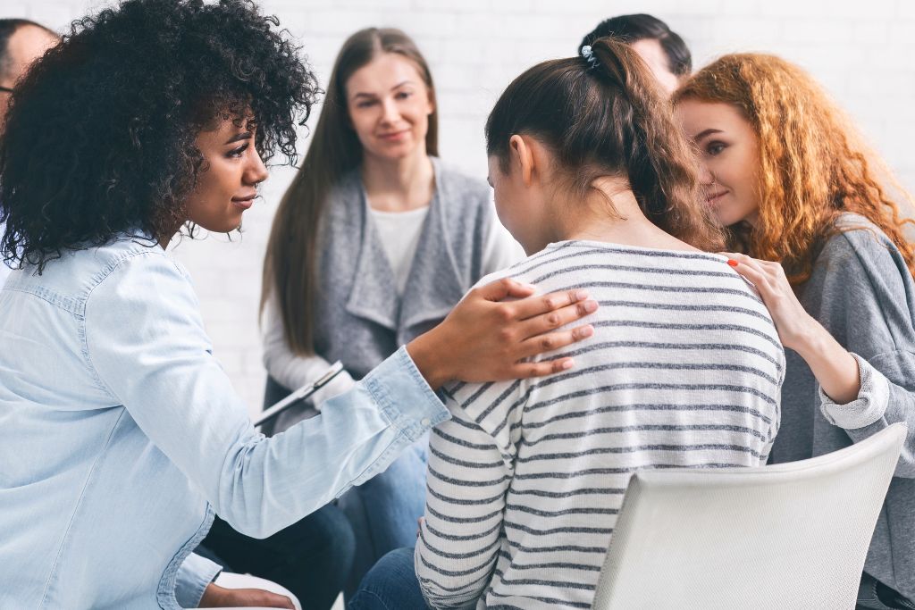 A group of people in a circle offering one person some support - Which Rehab