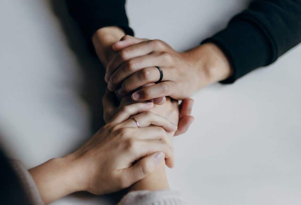 Two people holding hands in a supportive manner - How Much Does Rehab Cost - Which Rehab