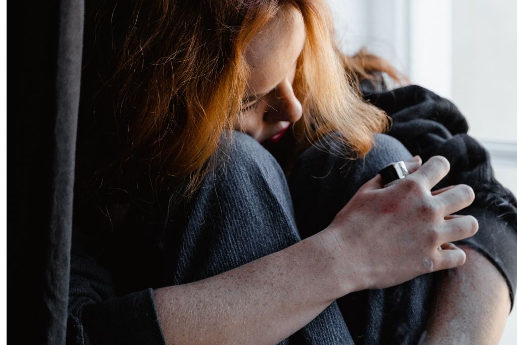 Woman with red hair stressed hugging her knees for comfort - Which Rehab